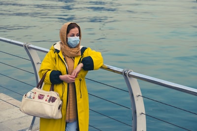 During the day, a yellowish-white jacket, wearing blue goggles man standing on the ship
